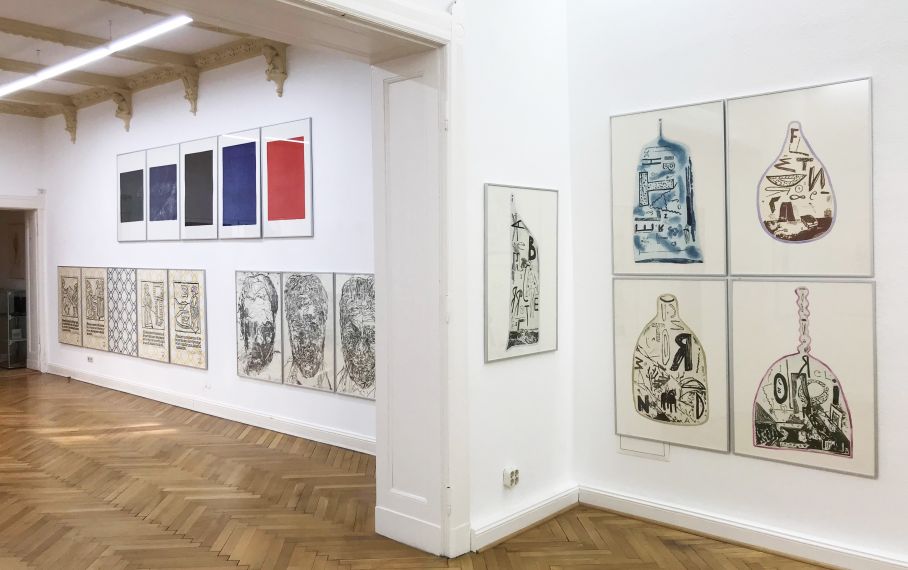 Ausstellungsansicht. An den Wänden hängen Gruppen von jeweils 5 großen Drucken von unterschiedlichen Künstlern