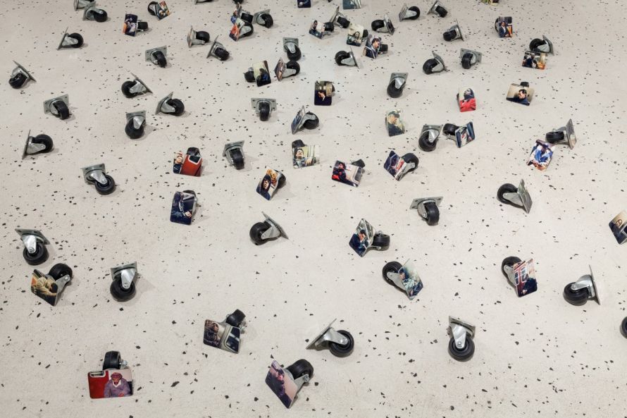 Viele Rollen liegen verteilt auf dem Boden, an jede Rolle ist ein Foto von einer schlafenden Person montiert