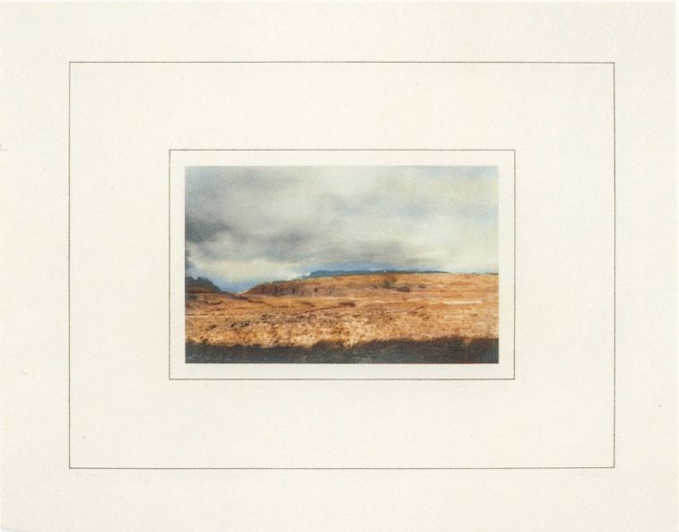 Druck von Gerhard Richter zeigt die Farbaufnahme einer kargen, bräunlichen Landschaft unter bewölktem Himmel, mit breitem weißen Rahmen