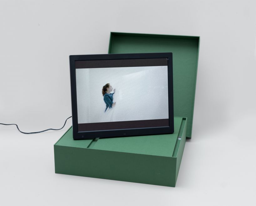 The edition ATEM by the artist Mehtap Baydu. A digital picture frame, on which a video of the performance is shown, stands on the green linen case made for it