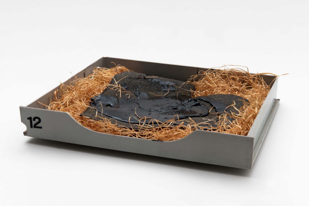 Multiple von KH Hödicke. In einer grauen Plastikschublade liegt Holzwolle und darauf Teerpappe in Form eines Herzens, das zusätzlich mit Teer übergossen wurde