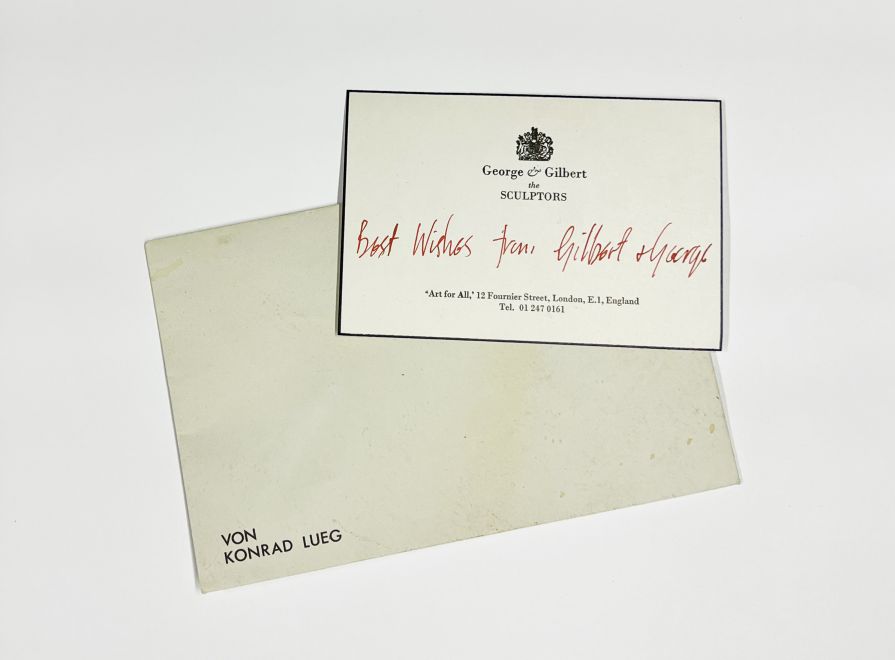 Edition von Konrad Lueg. Ein Briefumschlag auf dem VON KONRAD LUEG steht. Darauf eine Visitenkarte von George & Gilbert mit handschriftlich in rot „Best Wishes from Gilbert + George“