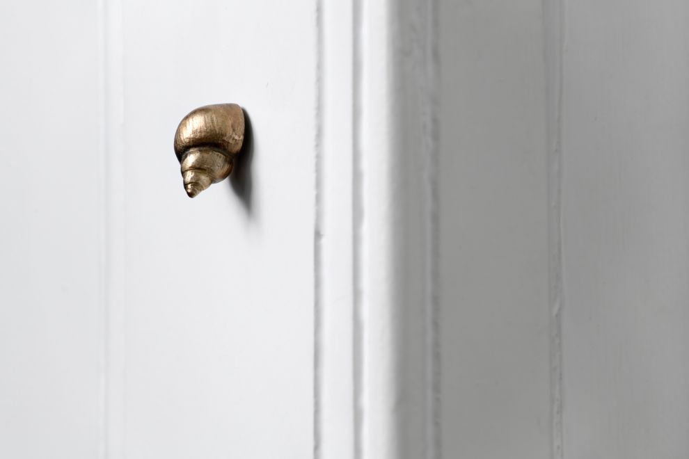 Edition von Ayse Erkmen, Nahaufnahme. Eine kleine Schnecke aus Bronze ist an einem Türrahmen montiert.