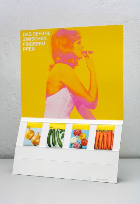 Edition by KP Brehmer. Imitates an advertising display. In the upper half, a pinup girl against a yellow background, pulling on a cigar. At the top left it says: THE FEELING BETWEEN FINGERTIPS. Four seed bags of different vegetables are mounted in the lower half.