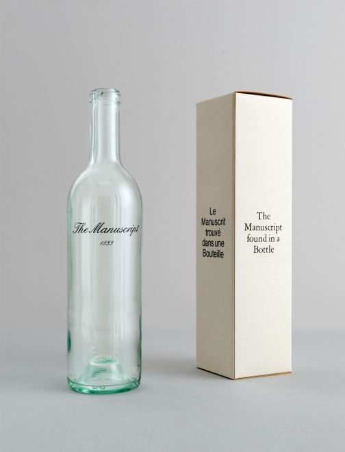 Edition von Marcel Broodthaers. Eine leere weiße Weinflasche, auf die „The Manuscript 1833“ in geschwungener Schrift gedruckt ist, steht neben einem passenden weißen Karton. Auf der einen Seite steht: Le Manuscript trouvé dans uns Bouteille, auf der anderen steht: The Manuscript found in a Bottle