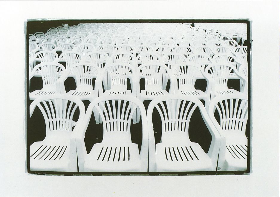 Offsetdruck von Olaf Metzel in Schwarz-Weiß zeigt Reihen von Monoblock-Stühlen, die das gesamte Bild ausfüllen, wie bei einer öffentlichen Veranstaltung