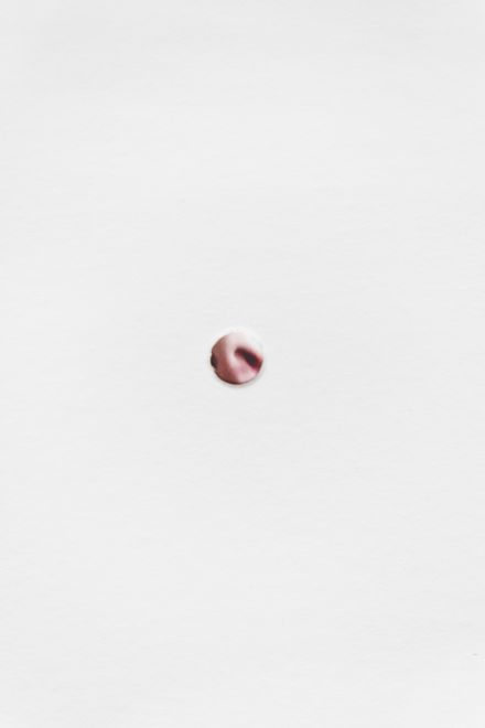 Detail aus einer Edition von Christine Moldrickx. Papier mit einem Loch, durch das man ein Foto der Nase der Künstlerin sieht