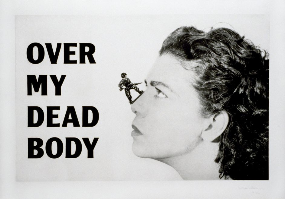 Druck von Mona Hatoum. Ein schwarz-weiß Portrait von Mona Hatoums Kopf. Auf ihrer Nase steht ein kleiner Spielzeugsoldat mit einem Gewehr in den Händen, das er auf sie richtet. Auf der linken Bildseite steht in fett schwarz OVER MY DEAD BODY