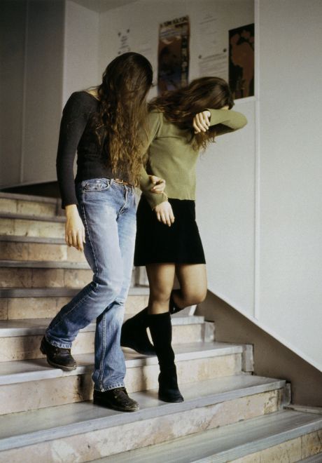 Offsetdruck von Bülent Sangar. Zwei junge Frauen gehen eine Treppe herunter, eine verdeckt ihr Gesicht mit ihrem Haar, eine mit ihrem Arm