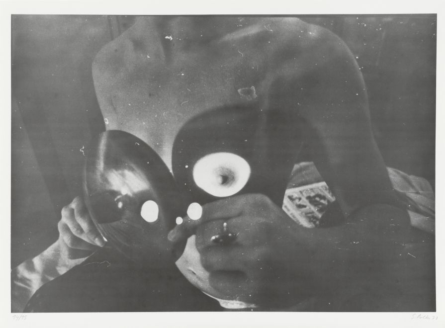 Offset print by Sigmar Polke. Blurred and heavily reworked b/w photo shows a naked woman. A beam of light is directed onto her chest with a lens.