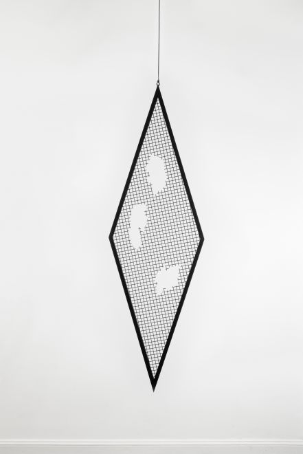 Edition von Sunah Choi. Ein rautenförmiges Gitterelement aus schwarzem, pulverbeschichtetem Stahl hängt an einem Seil von der Decke eines Galerieraumes. Aus dem Gitter wurden drei organische Formen gefräst.
