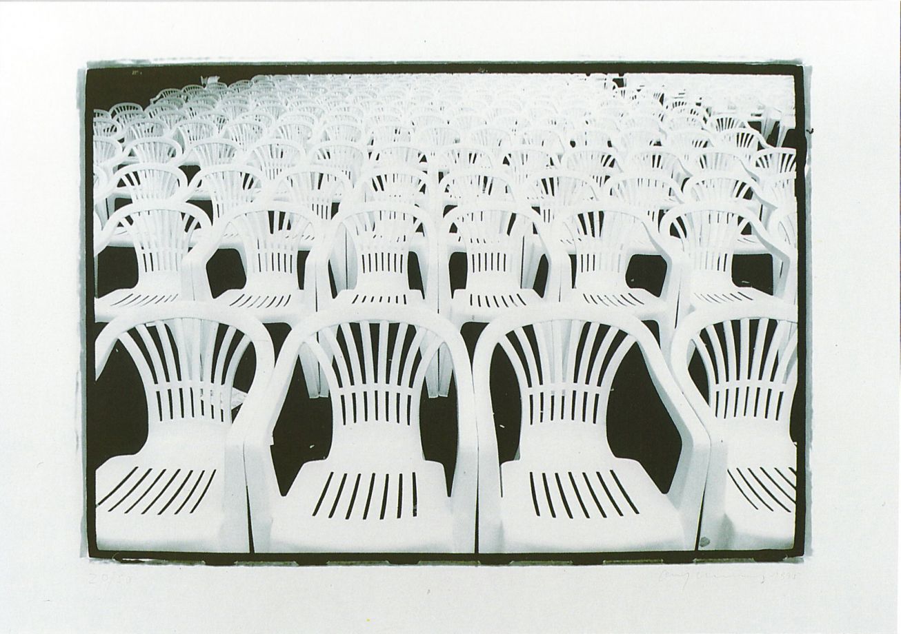 Offsetdruck von Olaf Metzel in Schwarz-Weiß zeigt Reihen von Monoblock-Stühlen, die das gesamte Bild ausfüllen, wie bei einer öffentlichen Veranstaltung