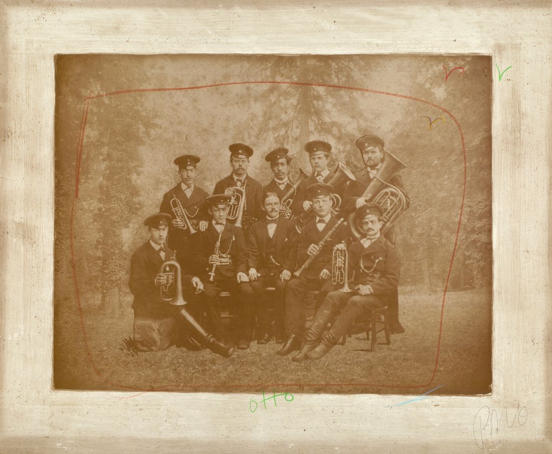 Kunstwerk von Nam June Paik. Eine Fotografie in Sepia zeigt eine MilitärBlaskapelle zu Beginn des 20. Jahrhunderts. Darüber hat Paik mit Kreide die Form eines Bildschirms und einige fliegende Vögel gemalt, sowie den Namen Otto geschrieben