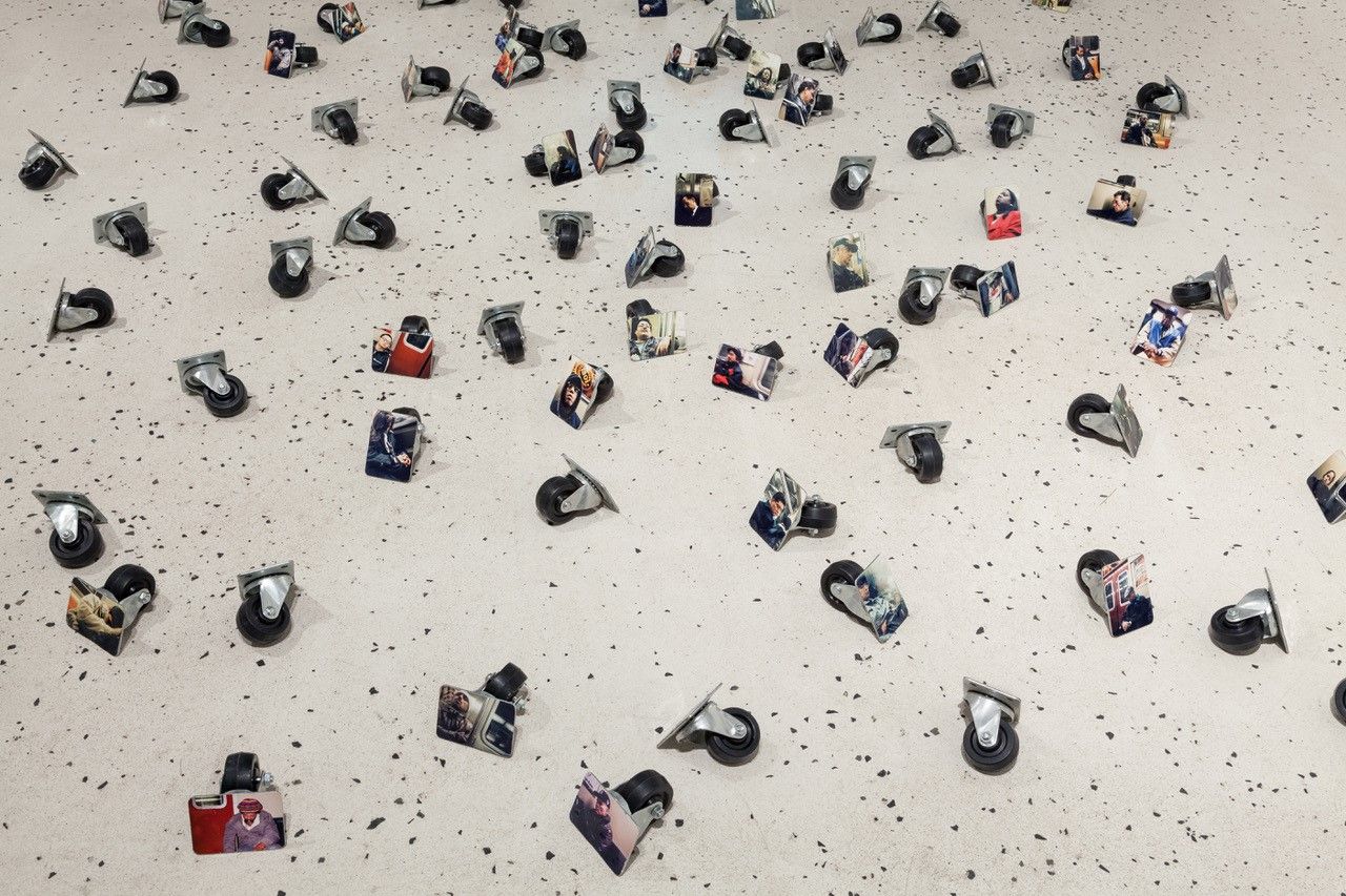 Viele Rollen liegen verteilt auf dem Boden, an jede Rolle ist ein Foto von einer schlafenden Person montiert