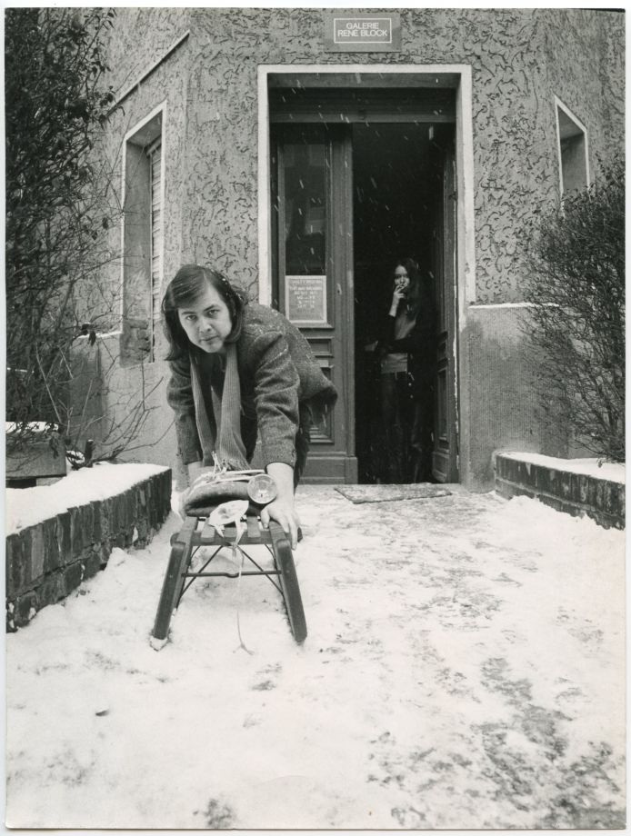 b/w photo showing a young René Block in the snow in front of the entrance to his gallery. He is leaning forward and pushing the Sledge by Joseph Beuys towards the camera.