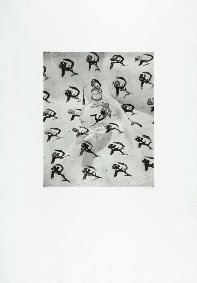 Graphic by Rosemarie Trockel shows a black and white photograph with a wide white frame. It shows a perfume bottle with a logo printed on it: a hammer and sickle, but the hammer has been replaced by a rose with thorns. The bottle stands on a piece of paper on which the logo is printed as a pattern