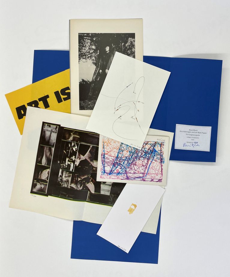 On a blue, unfolded folder lie 5 drawings and prints by various artists.