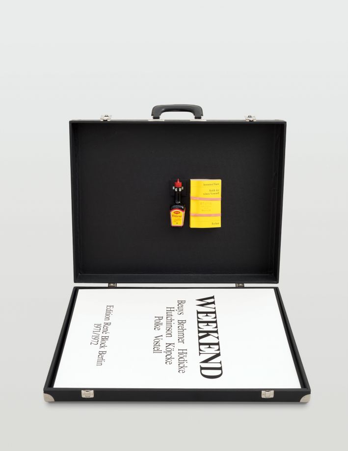 Edition Weekend. Ein aufgeklappter schwarzer Koffer. Im Deckel ist die Edition von Joseph Beuys montiert: eine Maggiflasche und Reclam Buch. Im Koffer liegt das Deckblatt für die Grafiken oben auf. Darauf ist zu lesen: WEEKEND. Beuys Brehmer Hödicke Hutchinson Köpcke Polke Vostell. Edition Rene Block Berlin 1971/1972